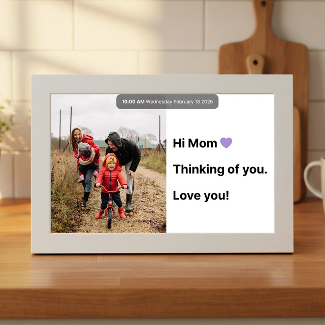 Memoryboard digital display on a kitchen counter showing a family photo and a message that reads “Hi Mom 💜 Thinking of you. Love you!” sent from the Memoryboard app.